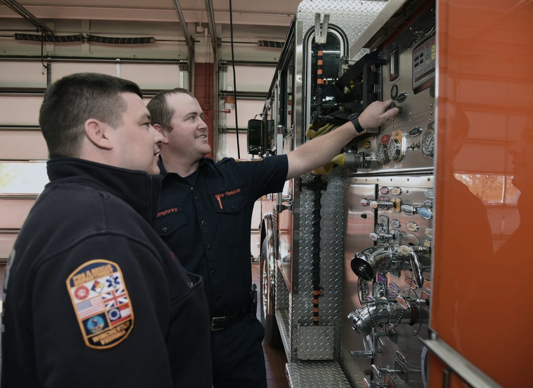 Two firefighters at an engine pump panel